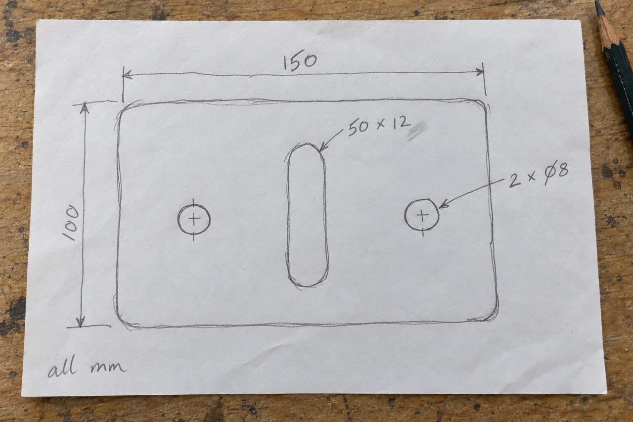 An uneven pencil sketch of a plate with two holes and a central slot, with handwritten dimensions on paper