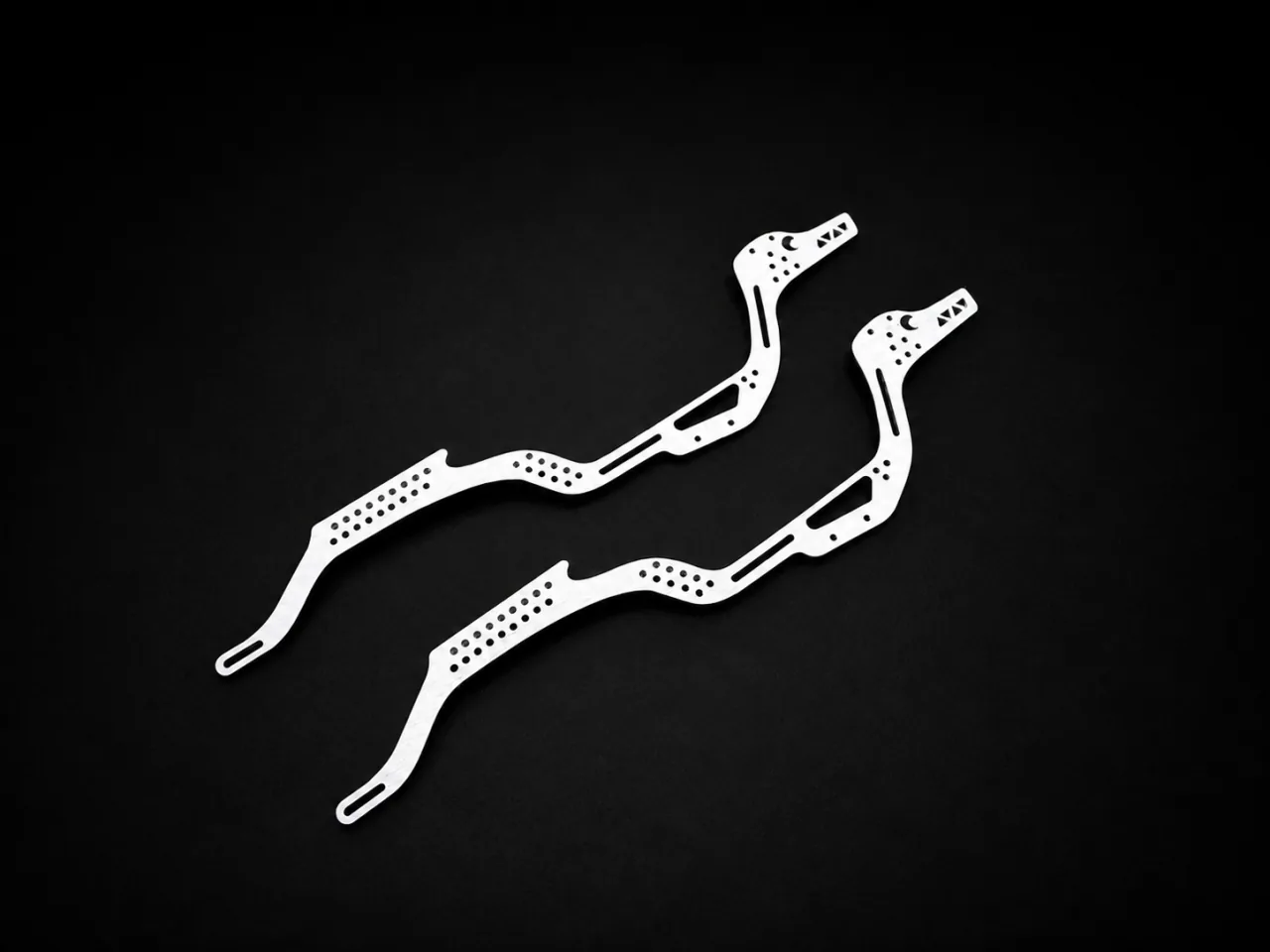 Two long laser-cut metal profiles with rows of small holes and narrow slots